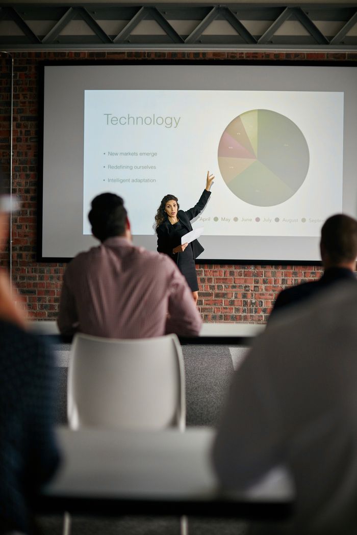 A presenter gesturing toward a slide during an educational seminar