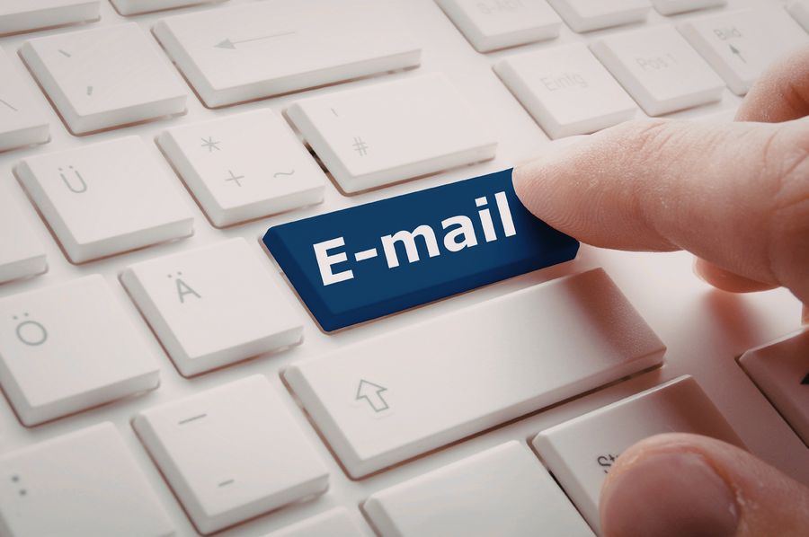 A finger pressing a blue E-mail key on a keyboard